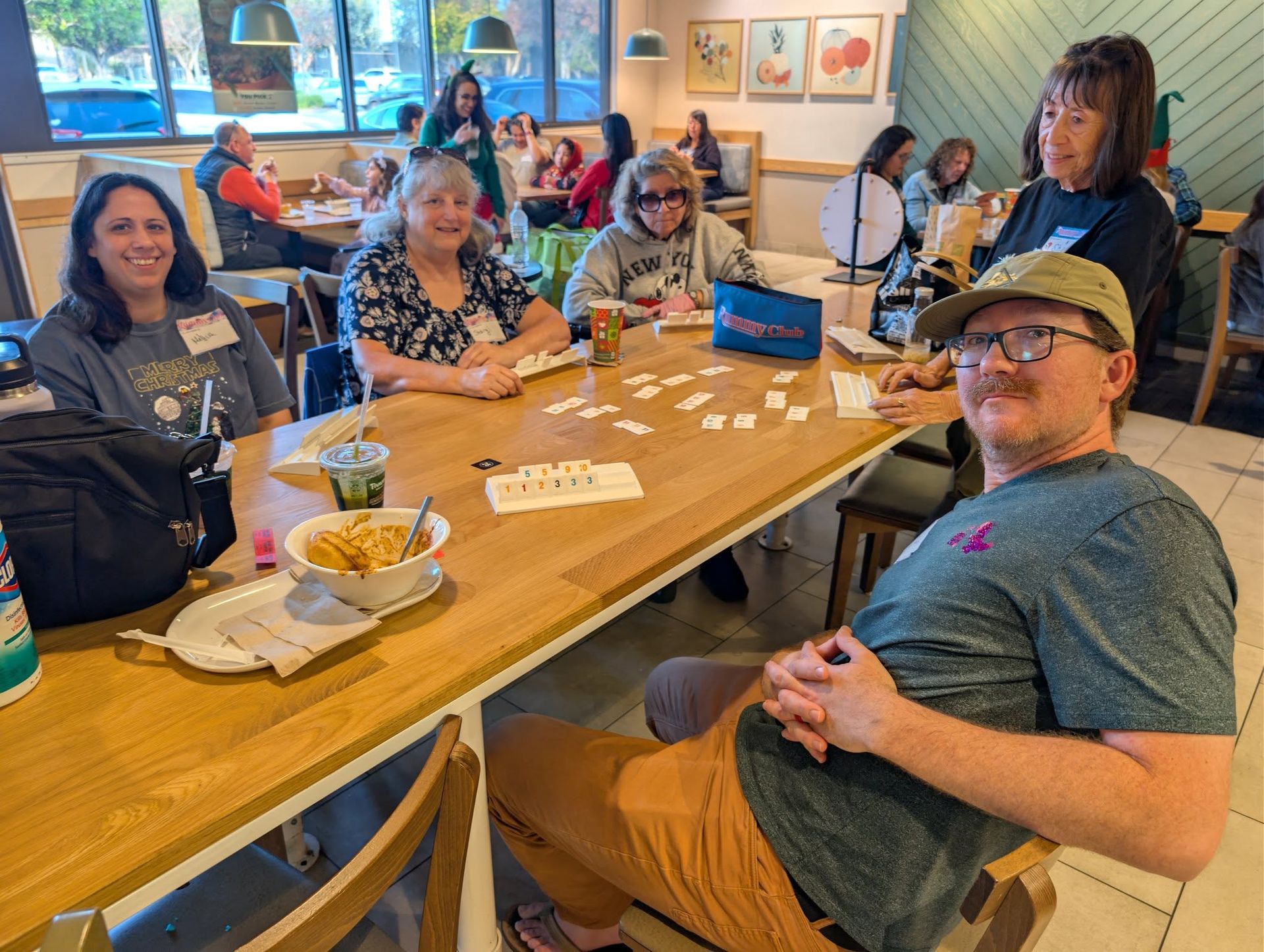 Rummy Club players at a community event, including a man in a cap